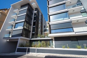 Un immeuble résidentiel moderne à plusieurs étages, doté de balcons, de grandes fenêtres et d’un toit plat.