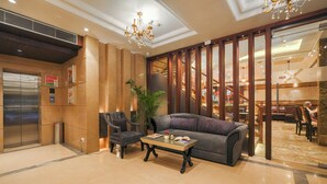 A lobby with a sofa, armchair, and coffee table, an elevator, and a staircase leading to another floor. - BluSalzz Select City Centre near Golden Temple (Amritsar)