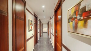 A hallway with wooden doors, framed artwork on the walls, and a polished floor. - BluSalzz Select City Centre near Golden Temple (Amritsar)