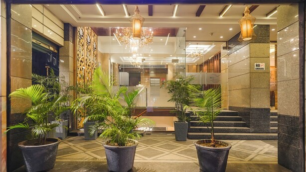 A hotel entrance with a modern design, featuring a reception desk, a chandelier, and potted plants. - BluSalzz Select City Centre near Golden Temple (Amritsar)