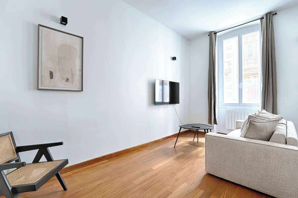 A modern living room with a sofa, a chair, a TV, and a painting on the wall.