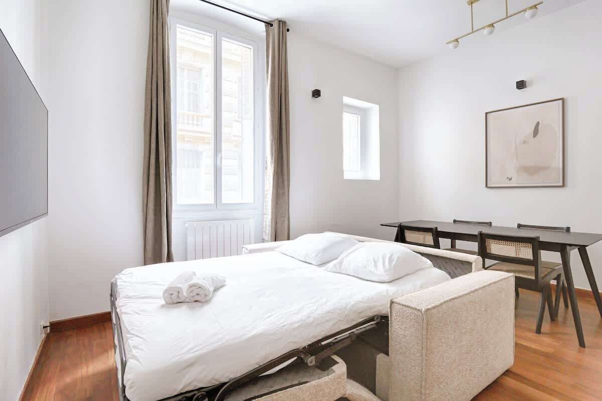 Una habitación de hotel pequeña con una cama, una mesita y una silla.