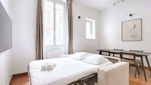 Una habitación de hotel pequeña con una cama, una mesita y una silla.