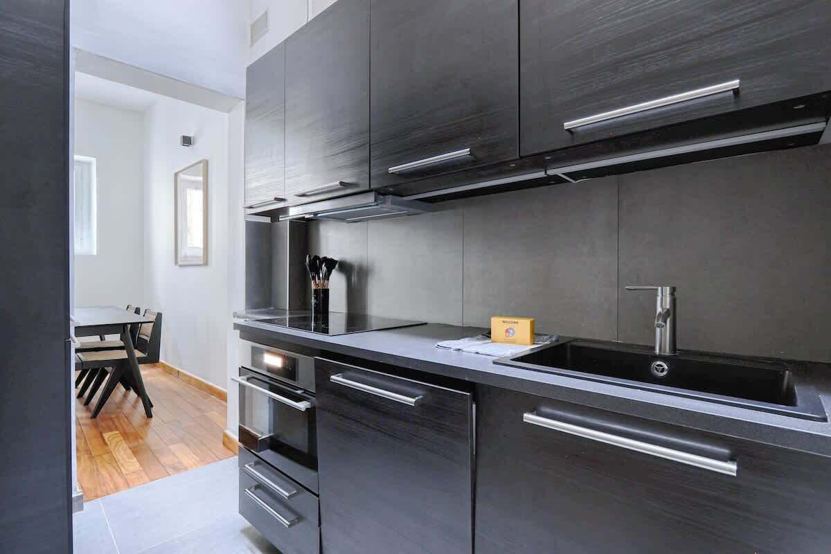 Una cocina moderna con armarios oscuros, electrodomésticos de acero inoxidable y un horno empotrado.