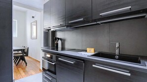 Una cocina moderna con armarios oscuros, electrodomésticos de acero inoxidable y un horno empotrado.