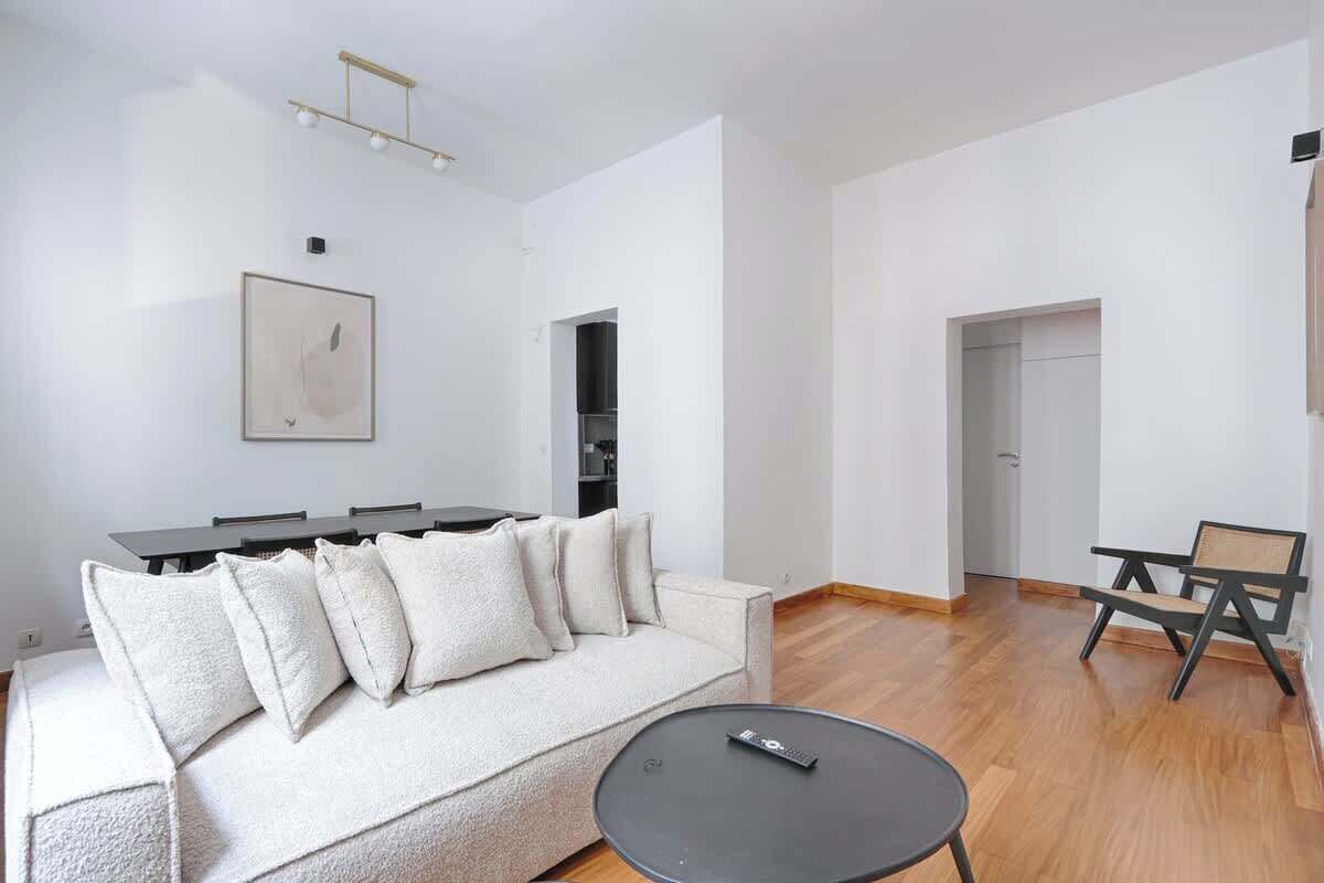 A modern living room with a sofa, a dining table, and a black coffee table.