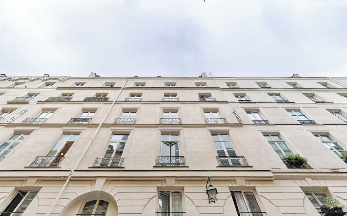 A multi-story building with a symmetrical facade, evenly spaced windows, and balconies with metal railings.