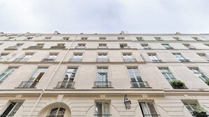 En bygning med flere etager, en symmetrisk facade, jævnt placerede vinduer og balkoner med gelændere i metal.