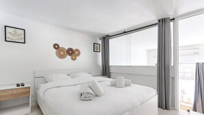 Et moderne hotelværelse med en stor seng, et sengebord og et vindue med gardiner.