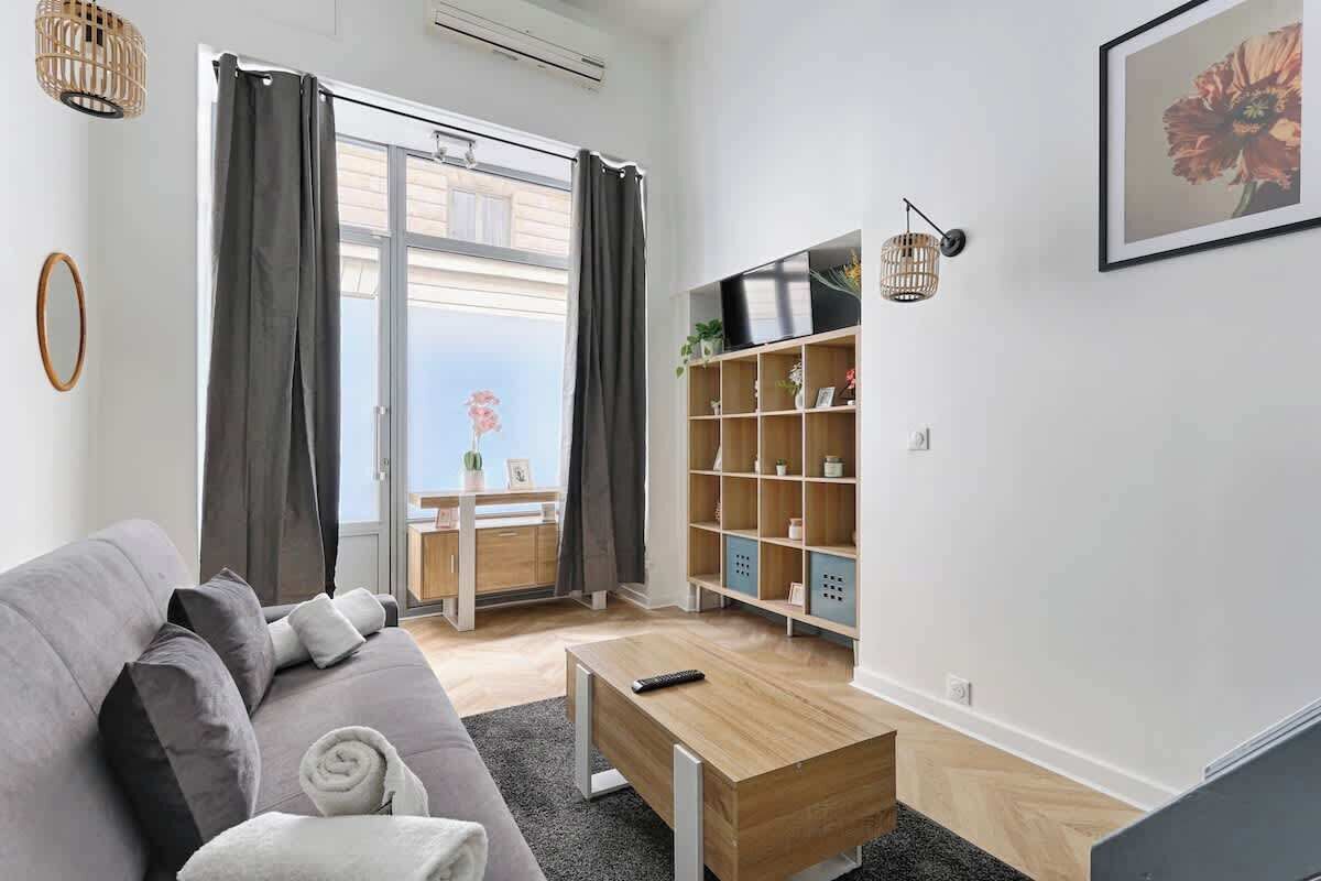 Una sala de estar moderna con un sofá gris, una mesa de centro de madera y una estantería.