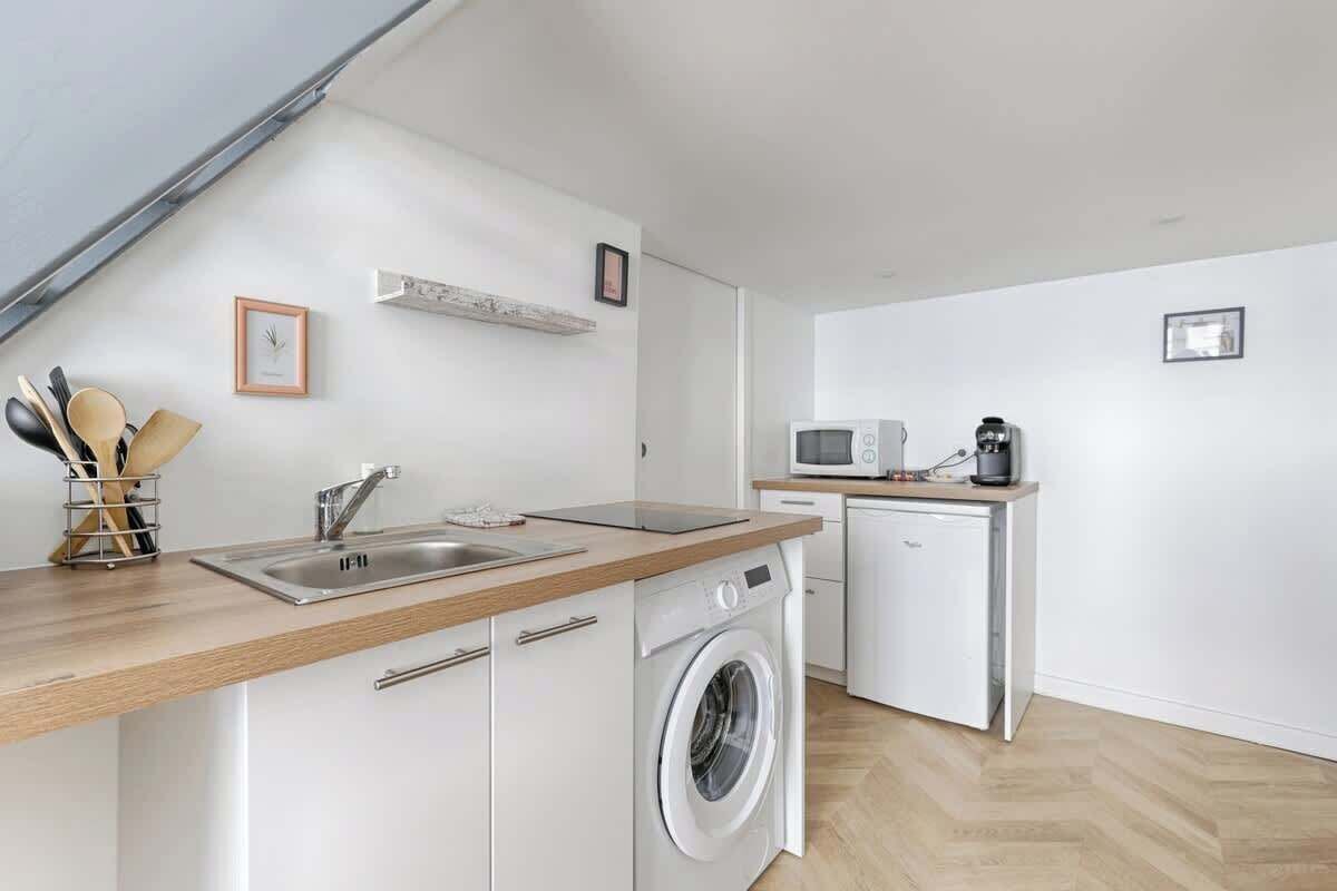 A compact kitchen with a washing machine, a microwave, and a coffee maker.