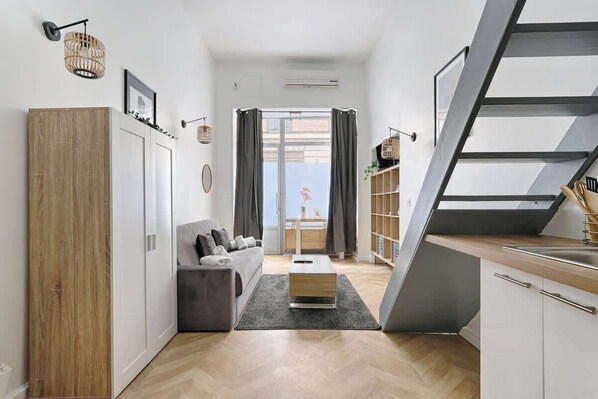 A modern apartment with a living area, kitchenette, and a staircase.