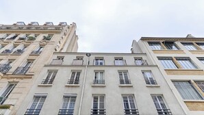 A multi-story building with a uniform facade, large windows, and balconies. - Batignolles Epinette Lovely Apartment 6P (Paris)
