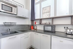 A modern kitchen with a built-in microwave, toaster, and kettle.