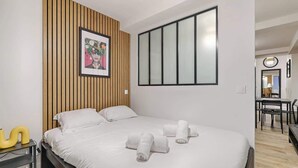 Et moderne hotelværelse med en stor seng, træpaneler, et indrammet billede og et stort vindue.