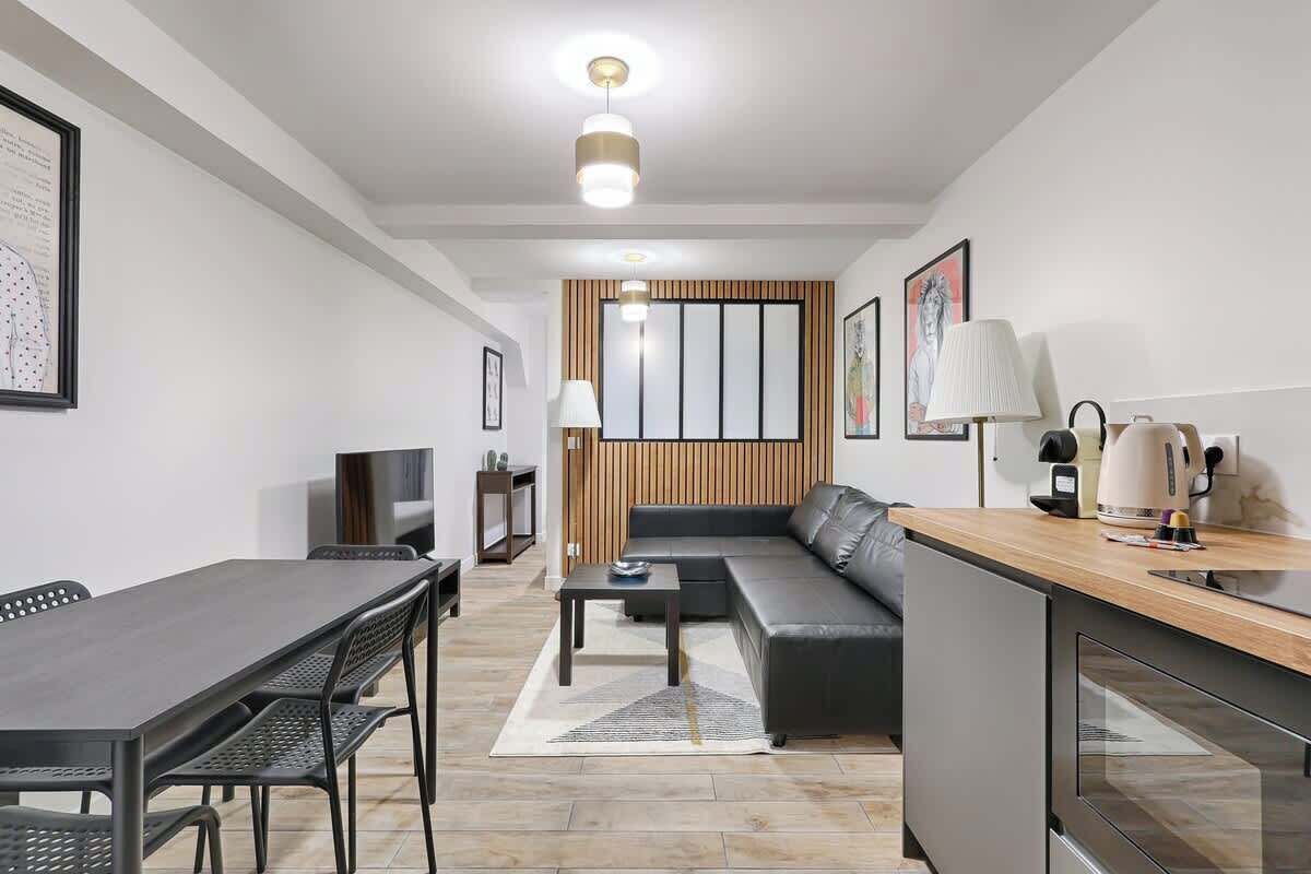 Un salon moderne comprenant un canapé, une table à manger avec des chaises, une table basse et un coin cuisine avec une cuisinière et des placards.