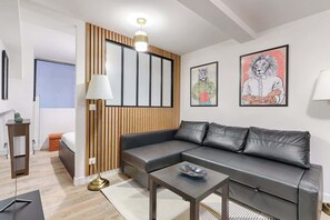 A modern living room with a grey leather sofa, a small coffee table, and a wooden accent wall.