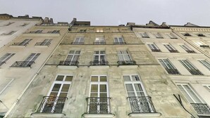 En bygning med flere etager, der har en ensartet facade, jævnt placerede vinduer og dekorative jernrækværk på balkonerne.