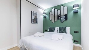 Een moderne hotelkamer met een groot bed, een groene accentmuur en meerdere spiegels.