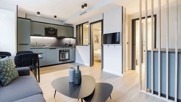 Een moderne woonkamer met een bank, een salontafel en een keuken op de achtergrond.