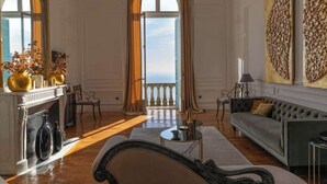 Uma sala de estar espaçosa com lareira, um sofá, uma mesa de centro e vista do céu através de grandes janelas.