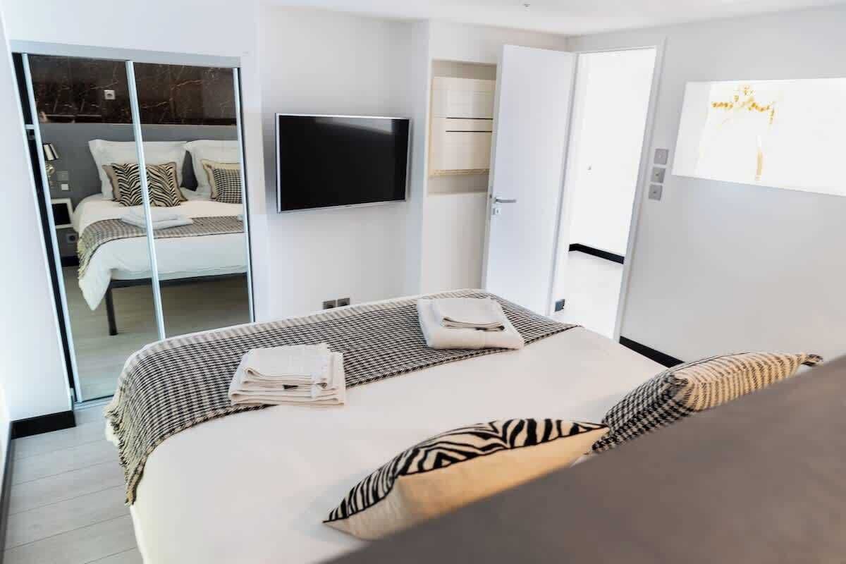 Ein modernes Hotelzimmer mit einem großen Bett, einem Flachbildfernseher, einem begehbaren Kleiderschrank und einer Schiebetür.