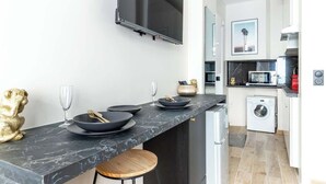 Una cucina moderna con un piano di lavoro in marmo, una TV a schermo piatto, una lavatrice e un forno a microonde.