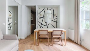 Una sala moderna con una mesa de comedor, dos sillas de mimbre, un sofá y una gran obra de arte abstracto en la pared.