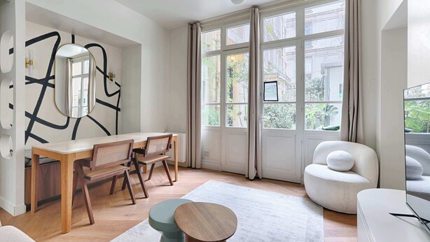Una sala de estar moderna con comedor, ventanas amplias y vistas a la ciudad.
