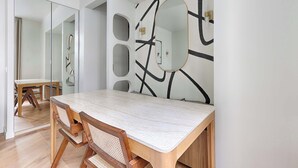 Un comedor moderno con una mesa y sillas de madera, un espejo grande y arte abstracto en la pared.