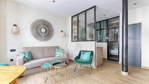 Ein modernes Wohnzimmer mit einer Couch, zwei kleinen Tischen, einem Sessel und einem großen Wandventilator.