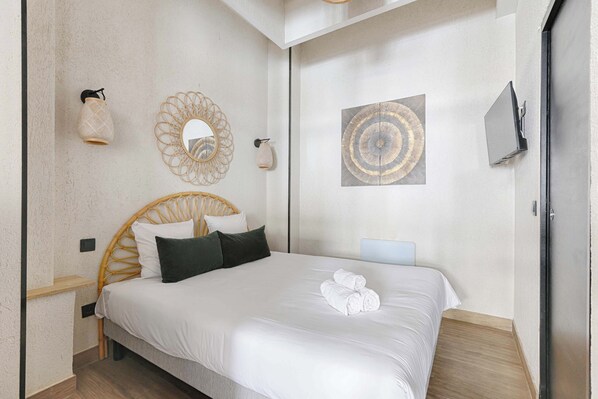 Un dormitorio ordenado con una cama grande, una mesita de noche, un televisor de pared y decoración mural.