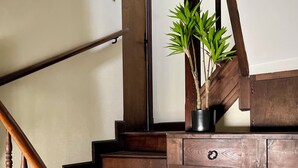 A wooden staircase with a handrail, a potted plant, and a wooden shelf with a drawer.