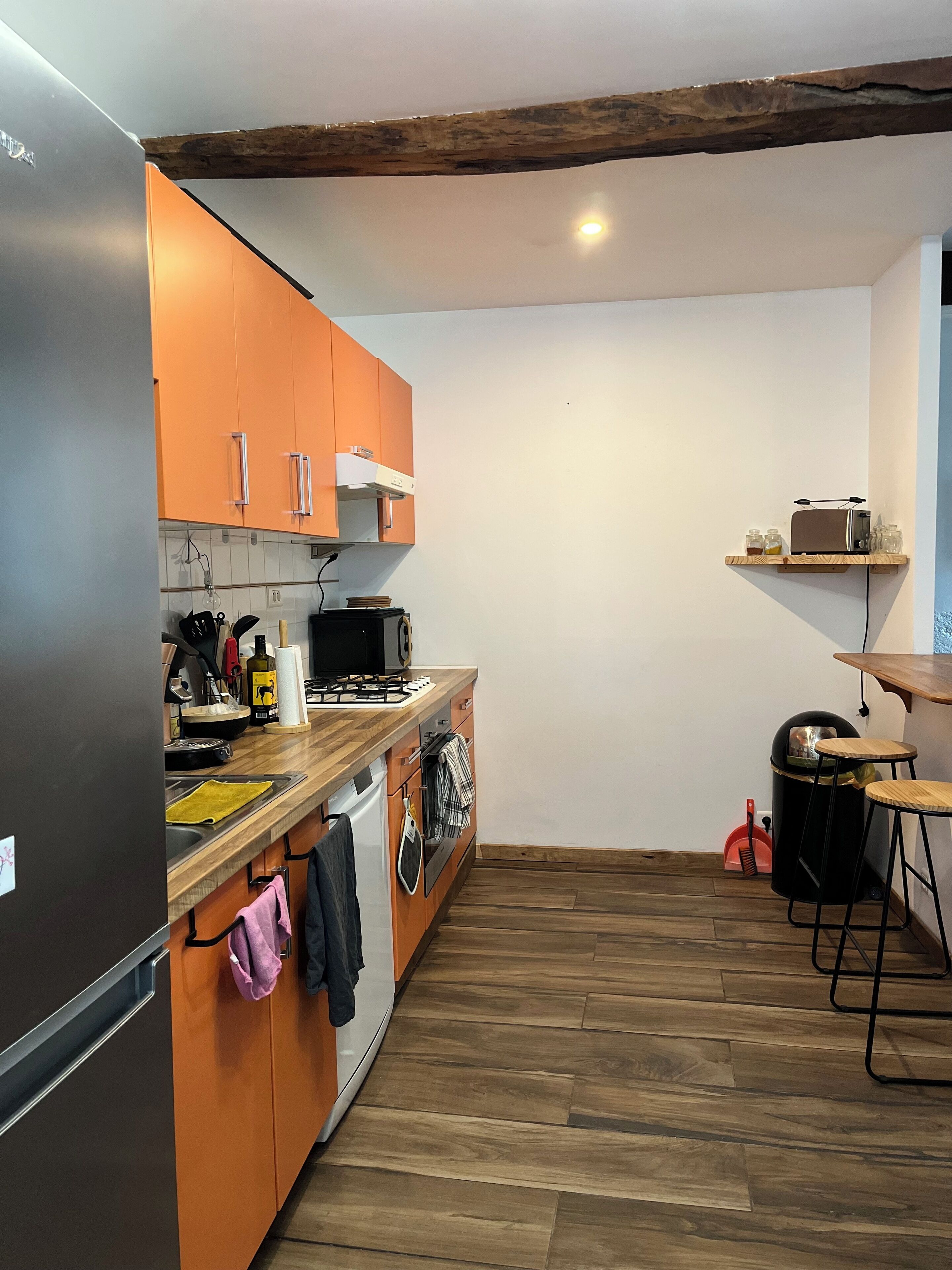 A kitchen with wooden cabinets, a stainless steel refrigerator, a microwave, and a wooden countertop.