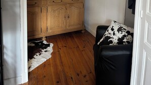 A room with a wooden cabinet, a mirror, a cowhide rug, and a black leather chair.