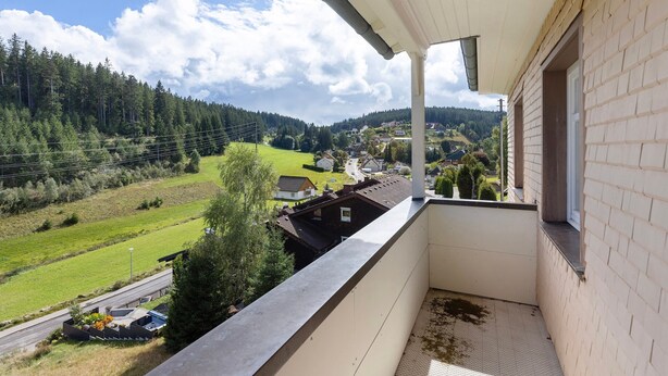 Ein Balkon mit Blick auf eine ländliche Landschaft, einschließlich Häusern und einer Straße.
