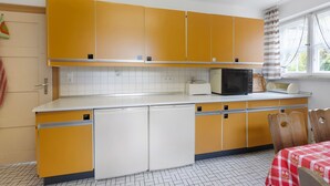 Eine Küche mit gelben Schränken, einer Mikrowelle, einem Toaster und einem Kühlschrank.