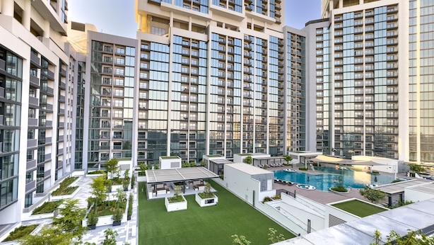 Un moderno edificio residenziale a più piani con numerosi balconi, una piscina sul tetto e terrazze curate.