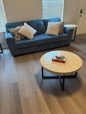 A living room with a blue sofa, a round coffee table, and a small side table.