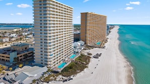 Um hotel à beira-mar com vários andares, piscina e praia adjacente ao oceano.