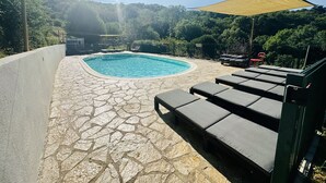 A swimming pool with stone flooring, lounge chairs, and a canopy. - Bella Dome - Cosy dome with panoramic mountain views, surrounded by beautiful nature (Riols)