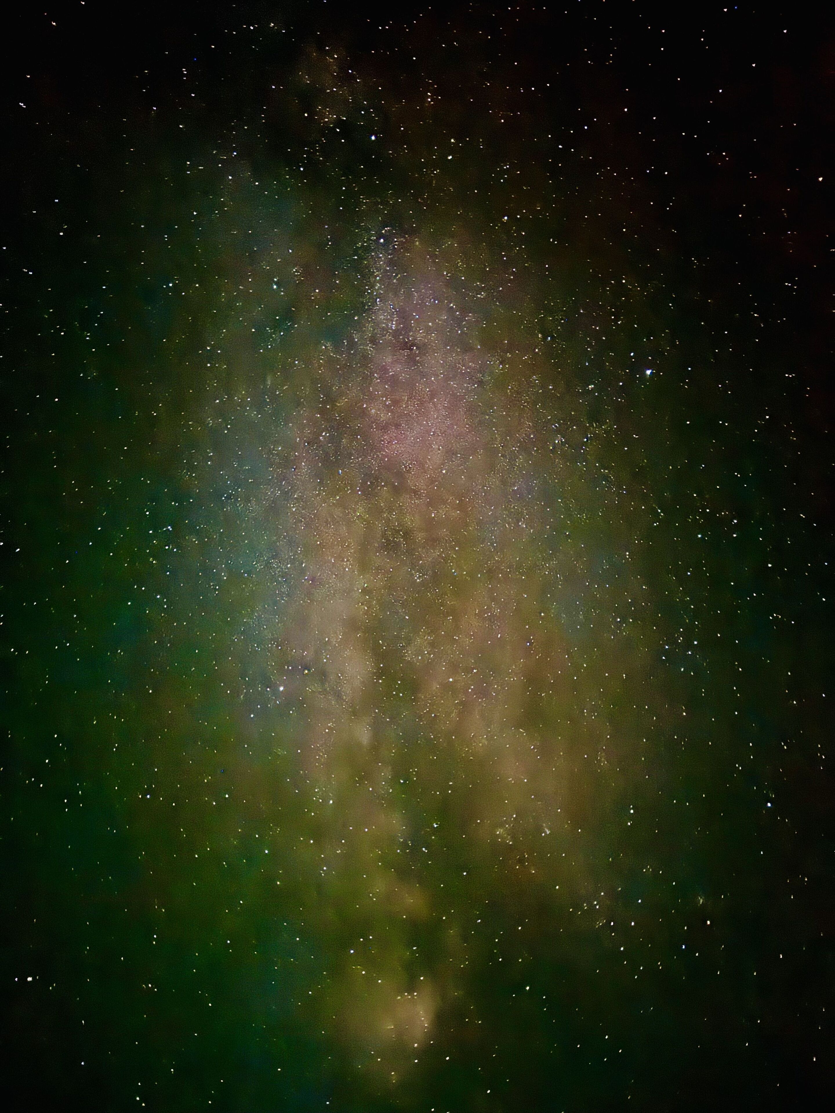 A starry night sky with a dense cluster of stars and a faintly visible nebula.