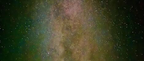 A starry night sky with a dense cluster of stars and a faintly visible nebula.