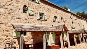 A stone building with multiple windows and a covered outdoor seating area. - Bella Dome - Cosy dome with panoramic mountain views, surrounded by beautiful nature (Riols)