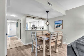 A modern kitchen with white cabinets, a wooden countertop, and a hanging light fixture.