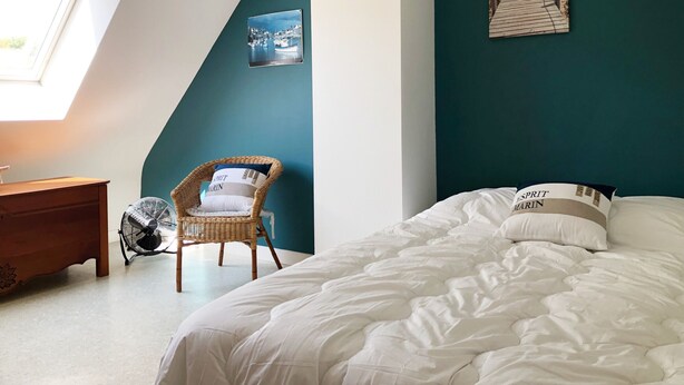 Une chambre à coucher avec un lit, une chaise, un ventilateur et une fenêtre.