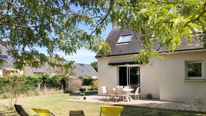 Un jardin avec une terrasse, un barbecue et des meubles de jardin.