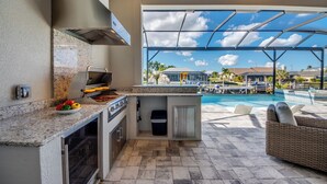 Une cuisine extérieure avec vue sur une piscine et un espace de détente.