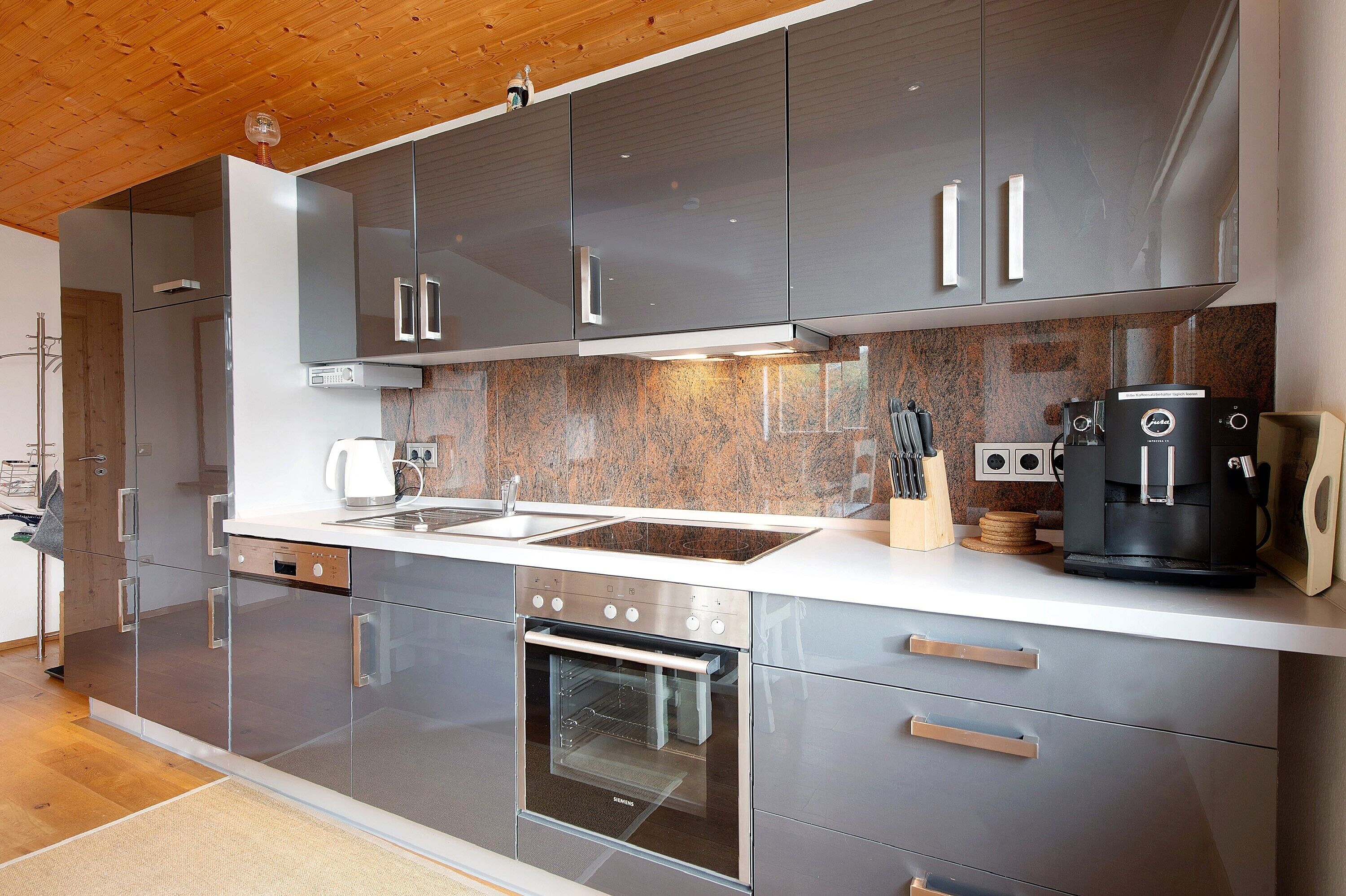A modern kitchen with stainless steel appliances, a built-in oven, and a coffee machine.