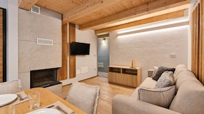 Un espace de vie moderne doté d’une cheminée, d’un plafond en bois et d’un téléviseur à écran plat fixé au mur.
